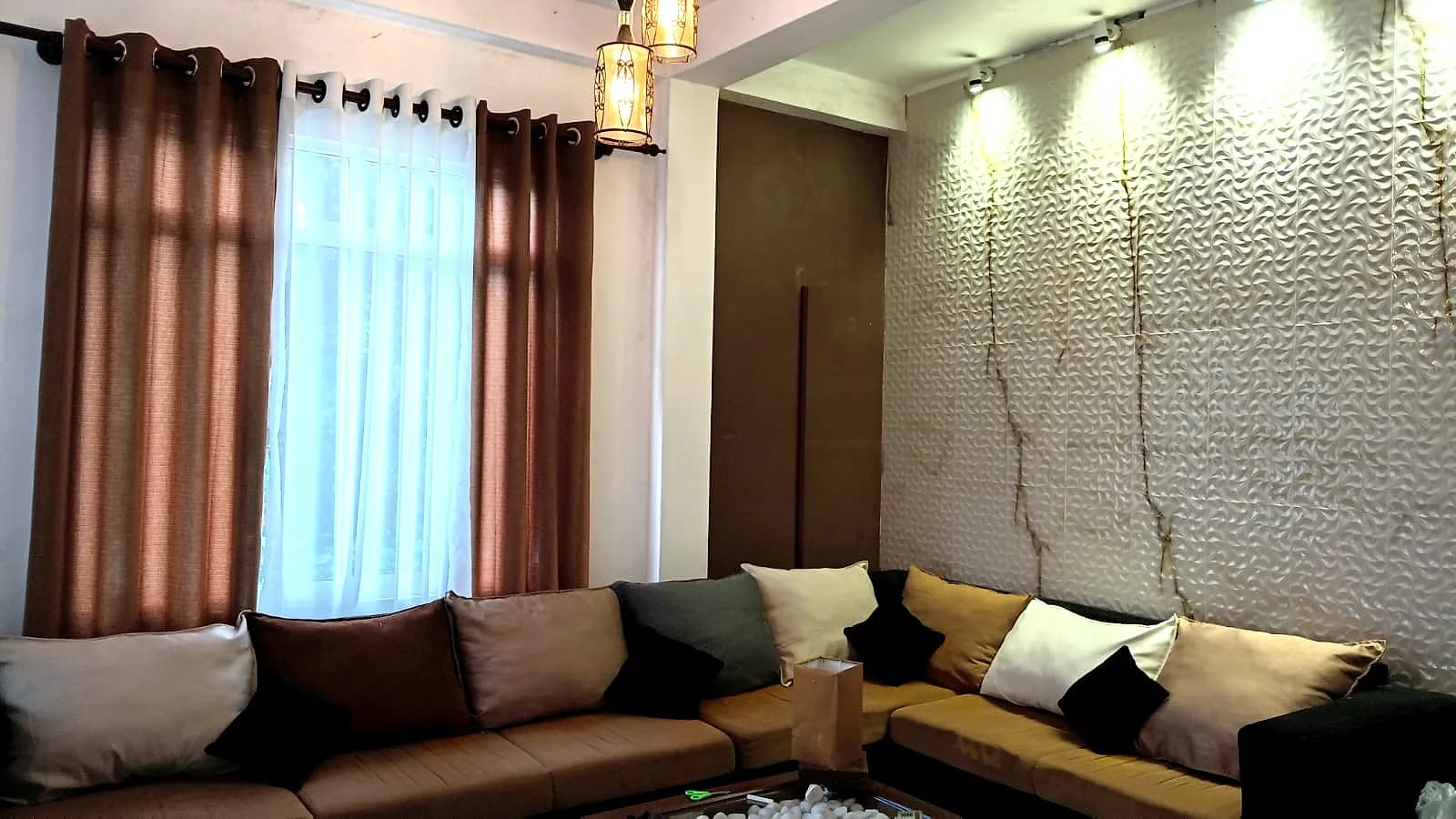 Open lounge with a deep sectional sofa and warm hanging lanterns