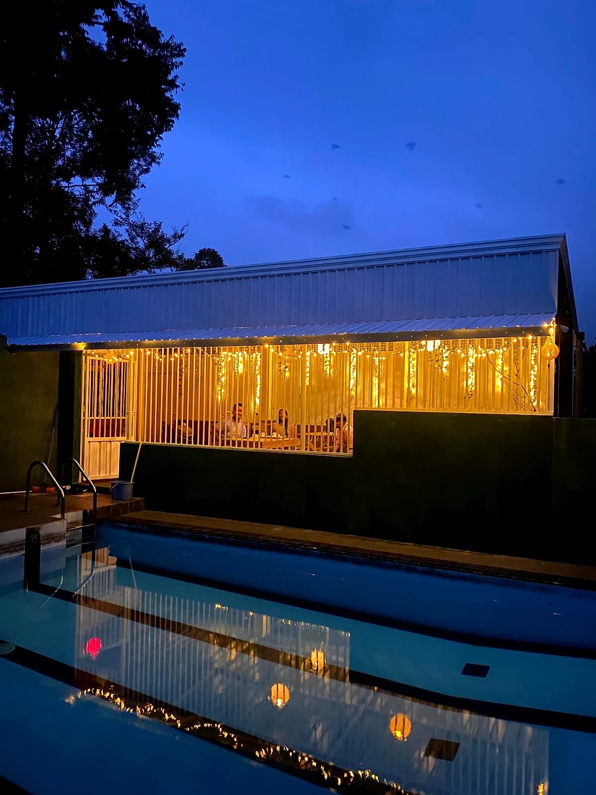 The pool at blue hour beside the fairy-lit dining pavilion at The Heights Retreat