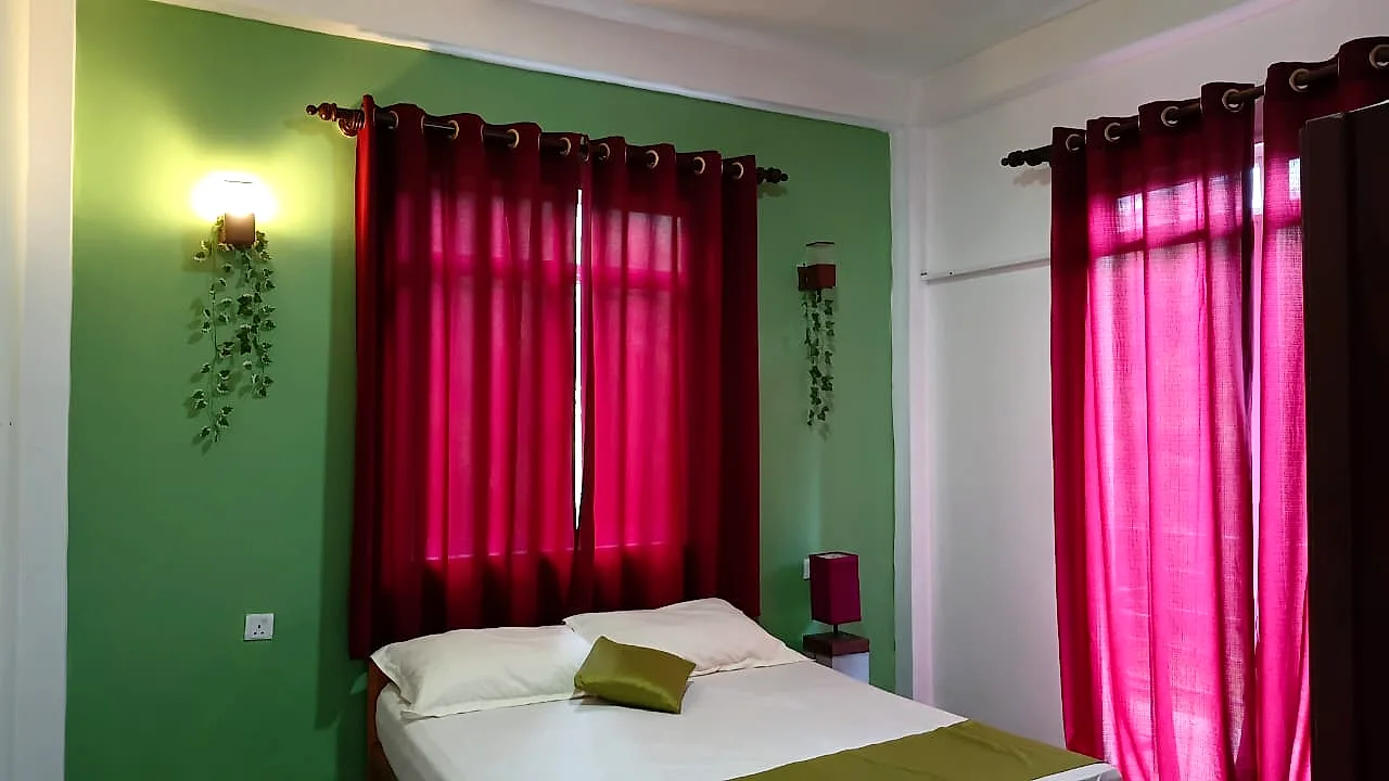 Bedroom with bright pink drapes, green walls and trailing ivy by a wall light